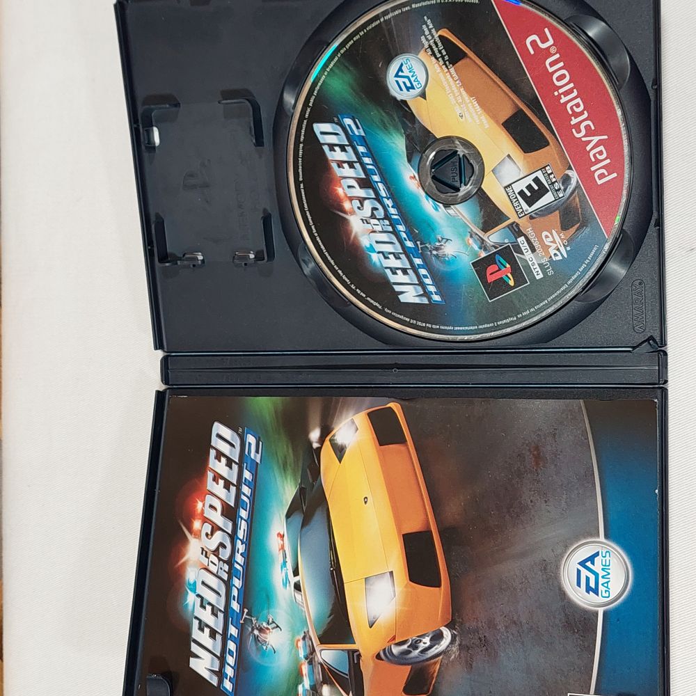 Open PlayStation 2 game case for Need for Speed Hot Pursuit 2, showing the game cover on the left and the disc on the right. The cover features a yellow sports car and EA Games and PlayStation 2 branding.